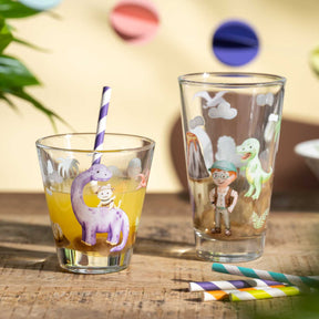 Trinkset BAMBINI AVVENTURA mit zwei Gläsern, farbigen Strohhalmen und Dino-Motiven auf Holztisch