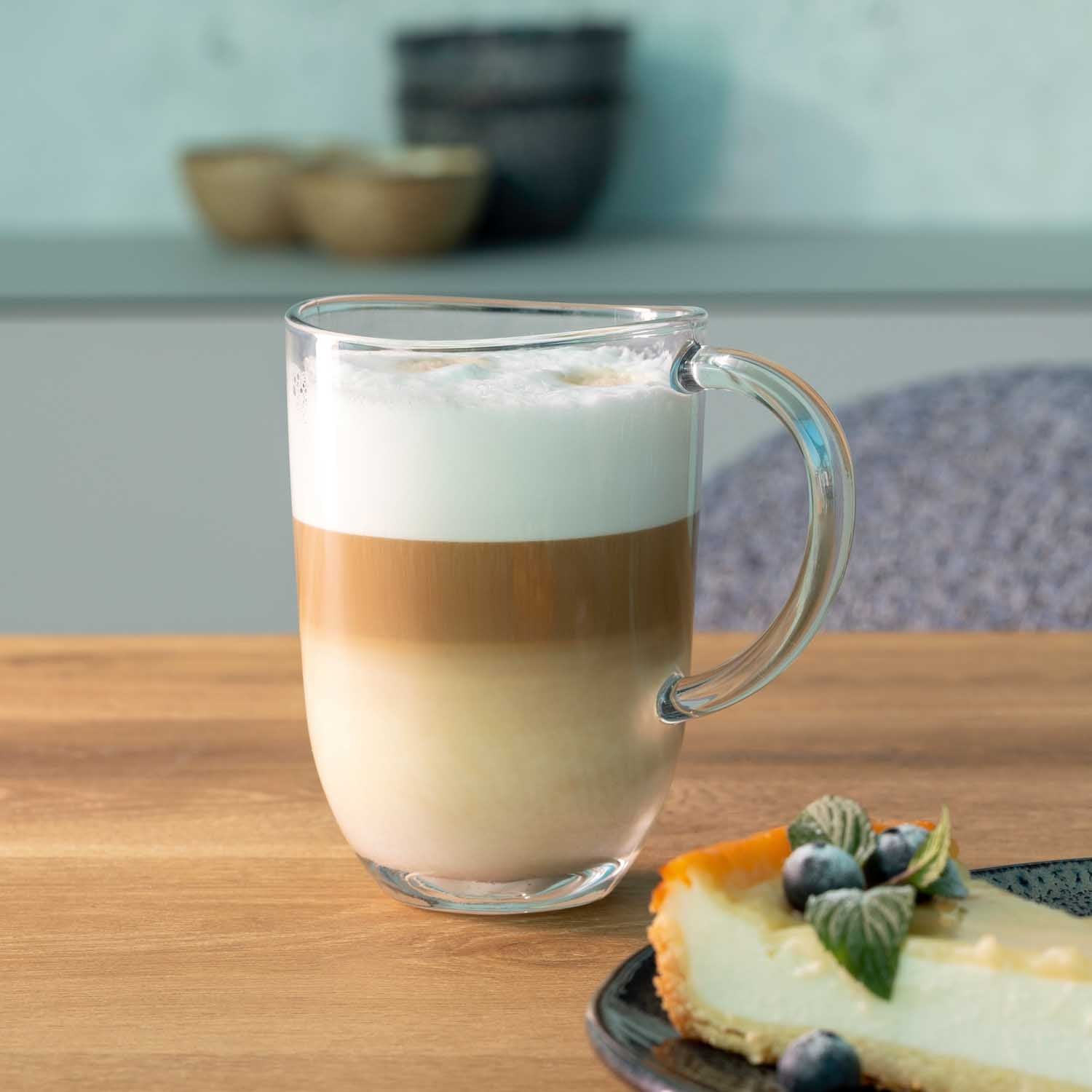 Tasse NAPOLI mit Cappuccino, daneben Kuchenstück mit Beeren auf Holztisch