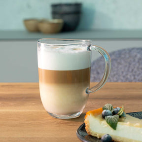 Tasse NAPOLI mit Cappuccino, daneben Kuchenstück mit Beeren auf Holztisch