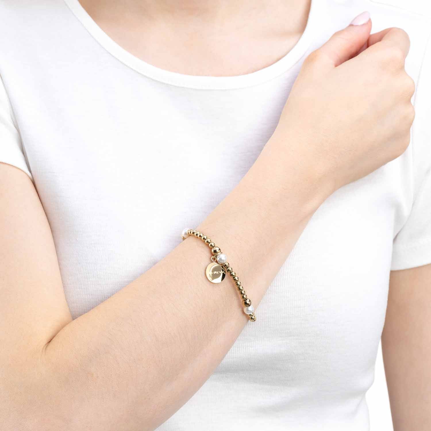 Armband MATHILDE gold an Frauenhand getragen, weißes Shirt