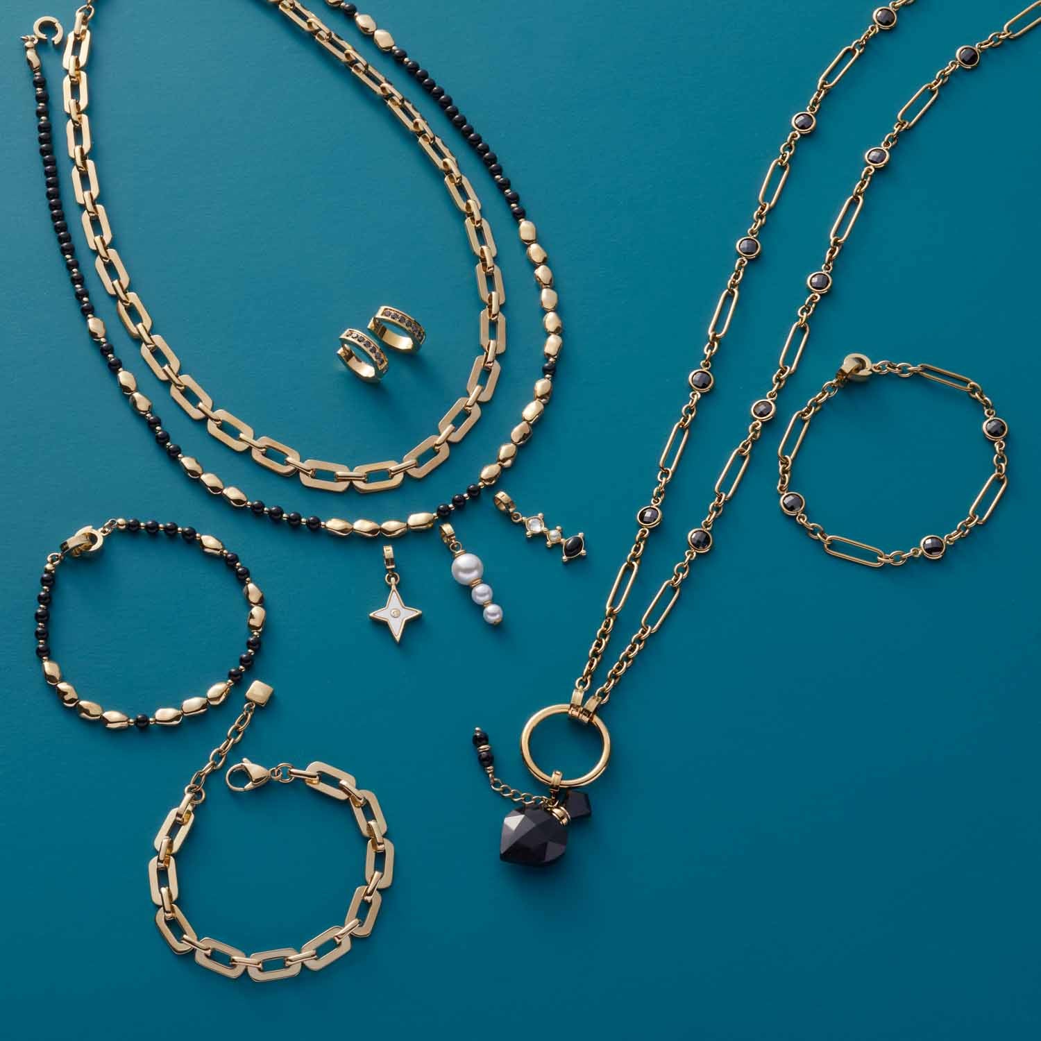 Halskette ORFEA gold mit Armbändern und Ohrringen auf blauem Hintergrund