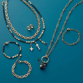 Halskette ORFEA gold mit Armbändern und Ohrringen auf blauem Hintergrund