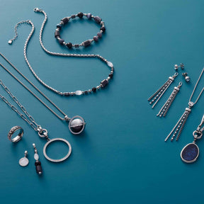 Schmuck-Kollektion auf blauem Hintergrund, silberne Halsketten, Armbänder, Ringe und Ohrringe mit Glassteinen