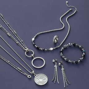 Silberner Schmuckset mit Halsketten, Armband, Ring und Ohrhänger auf violettem Hintergrund