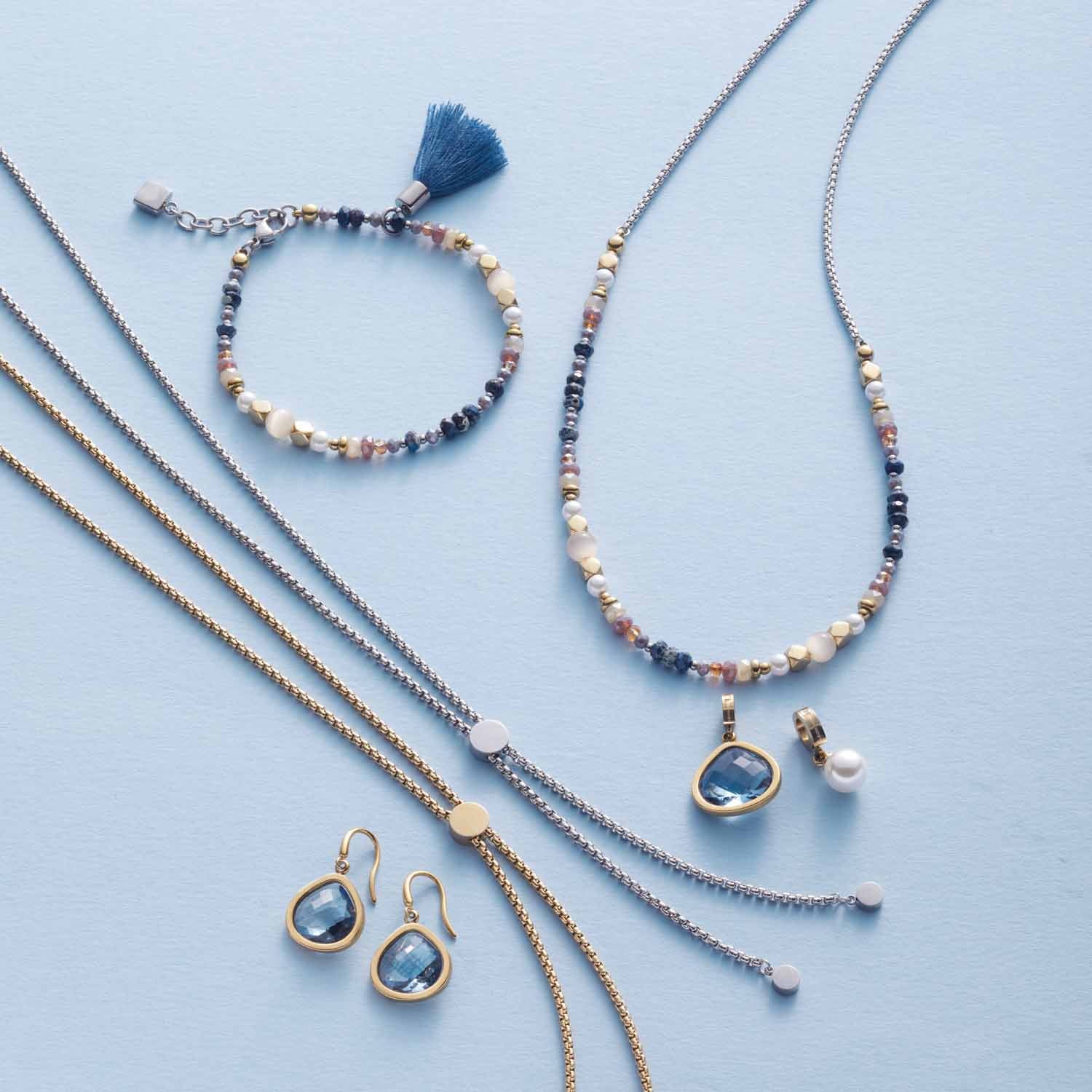 Halskette BABSI, Armband und Ohrringe aus Glasperlen in Blau-, Creme- und Rosatönen auf hellblauem Hintergrund