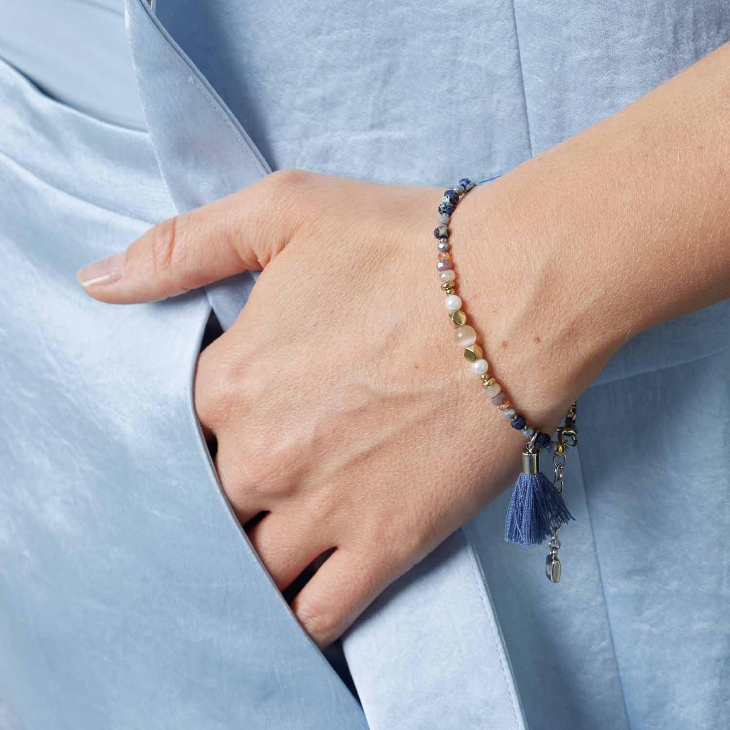 Armband BABSI mehrfarbig an weiblichem Handgelenk getragen, blaue Bluse