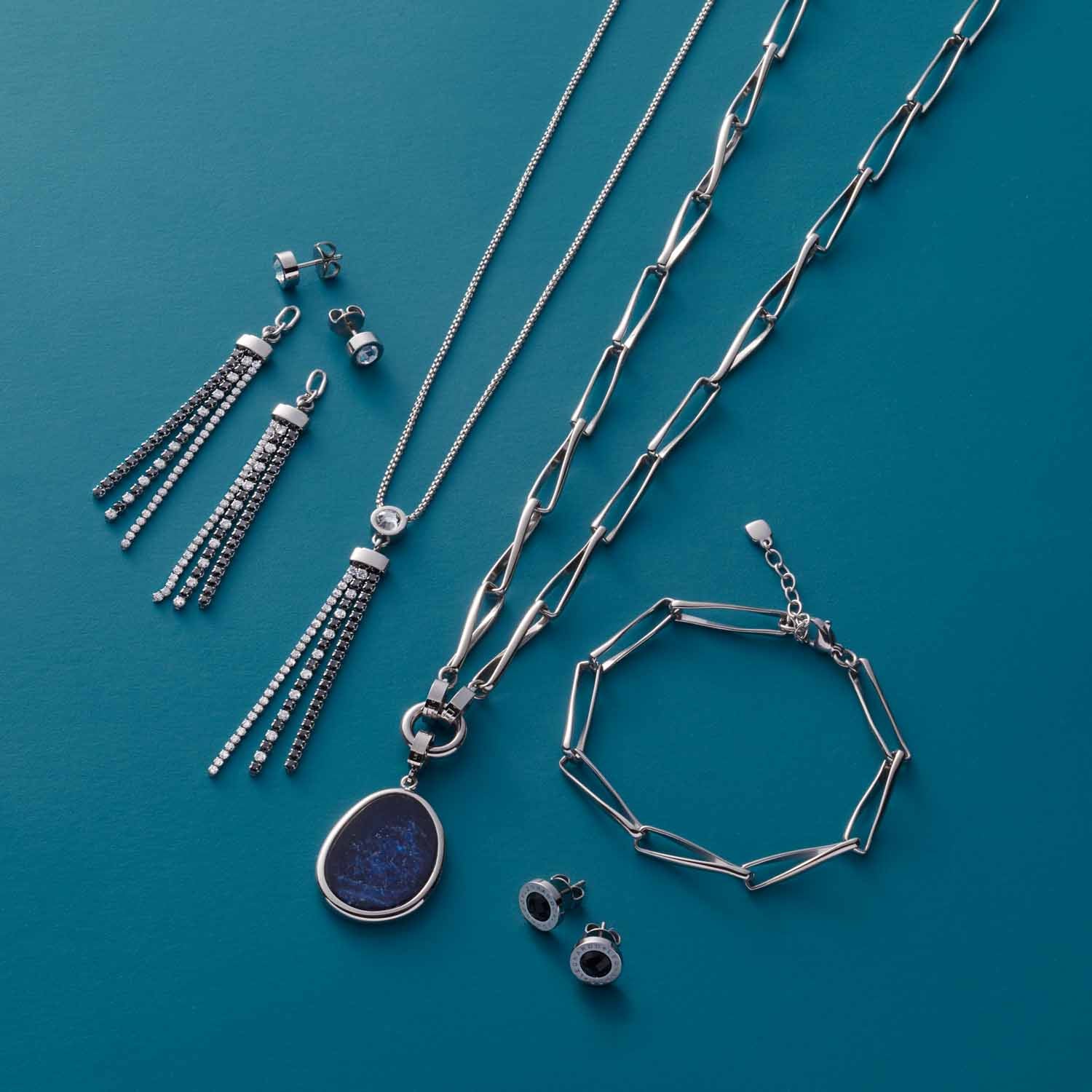 Schmuckkollektion mit Halskette ATURA, Ohrringen und Armband auf türkisblauem Untergrund