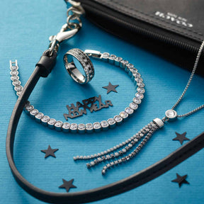 Halskette ATURA mit Glassteinen, Ring, Armband und Dekorationselementen auf blauem Hintergrund