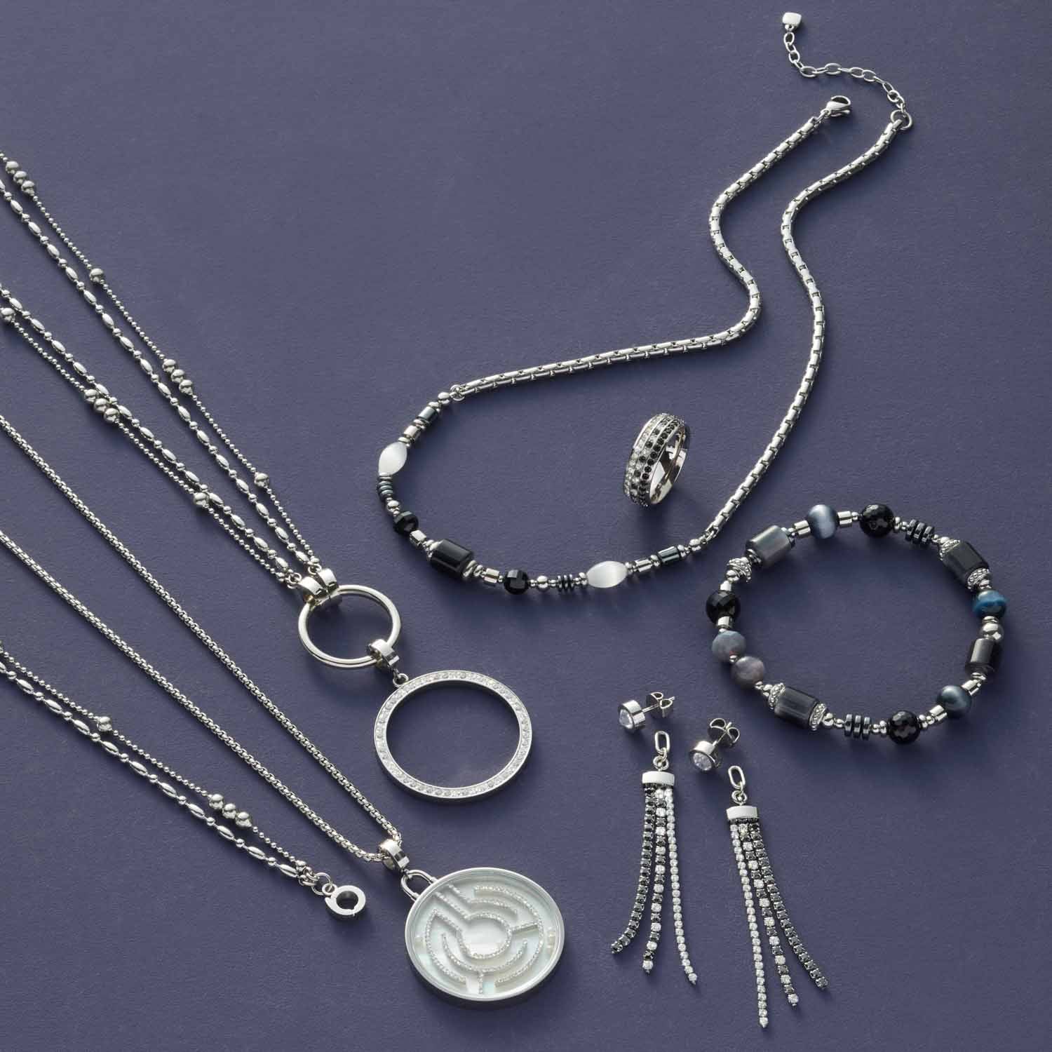 Schmuckkollektion mit Halsketten, Ringen, Armband und Ohrhaengern auf grauem Hintergrund