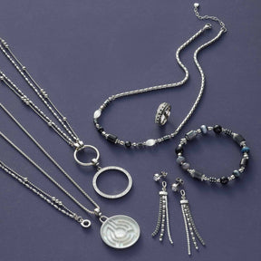 Schmuckkollektion mit Halsketten, Ringen, Armband und Ohrhaengern auf grauem Hintergrund