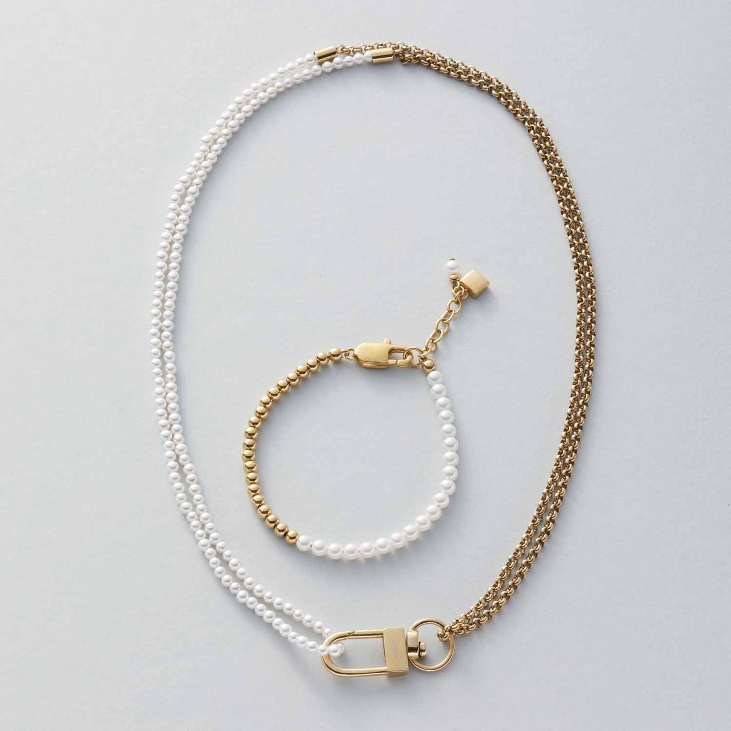 Halskette LUCINDA mit Perlen und Goldkugeln, dazu passendes Armband auf grauem Hintergrund