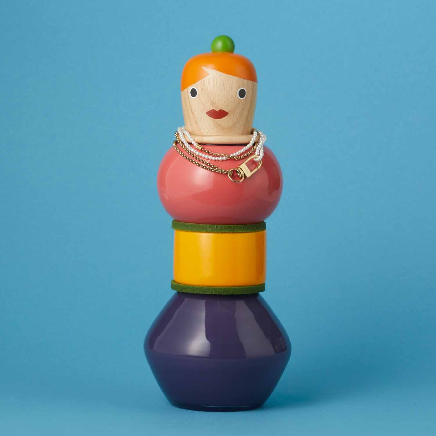 Bunte Holzfigur mit orangem Haar und Halskette auf blauem Hintergrund