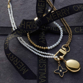 Armband LUCINDA gold mit Perlen, Muscheln und schwarzem Band auf grauem Untergrund