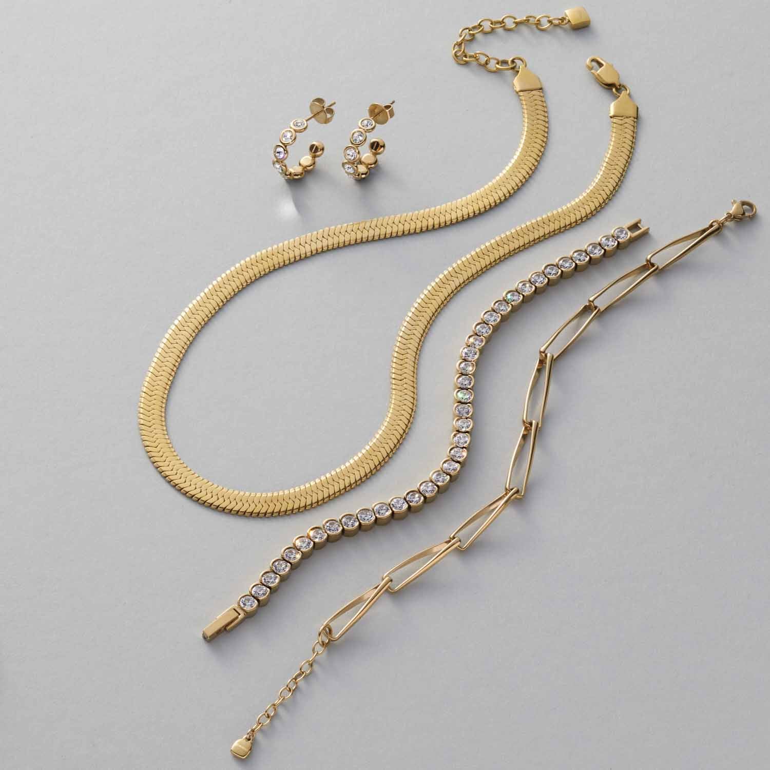 Armbänder und Ohrringe der Serie CREMONA in Gold und mit Zirkoniasteinen auf grauem Hintergrund