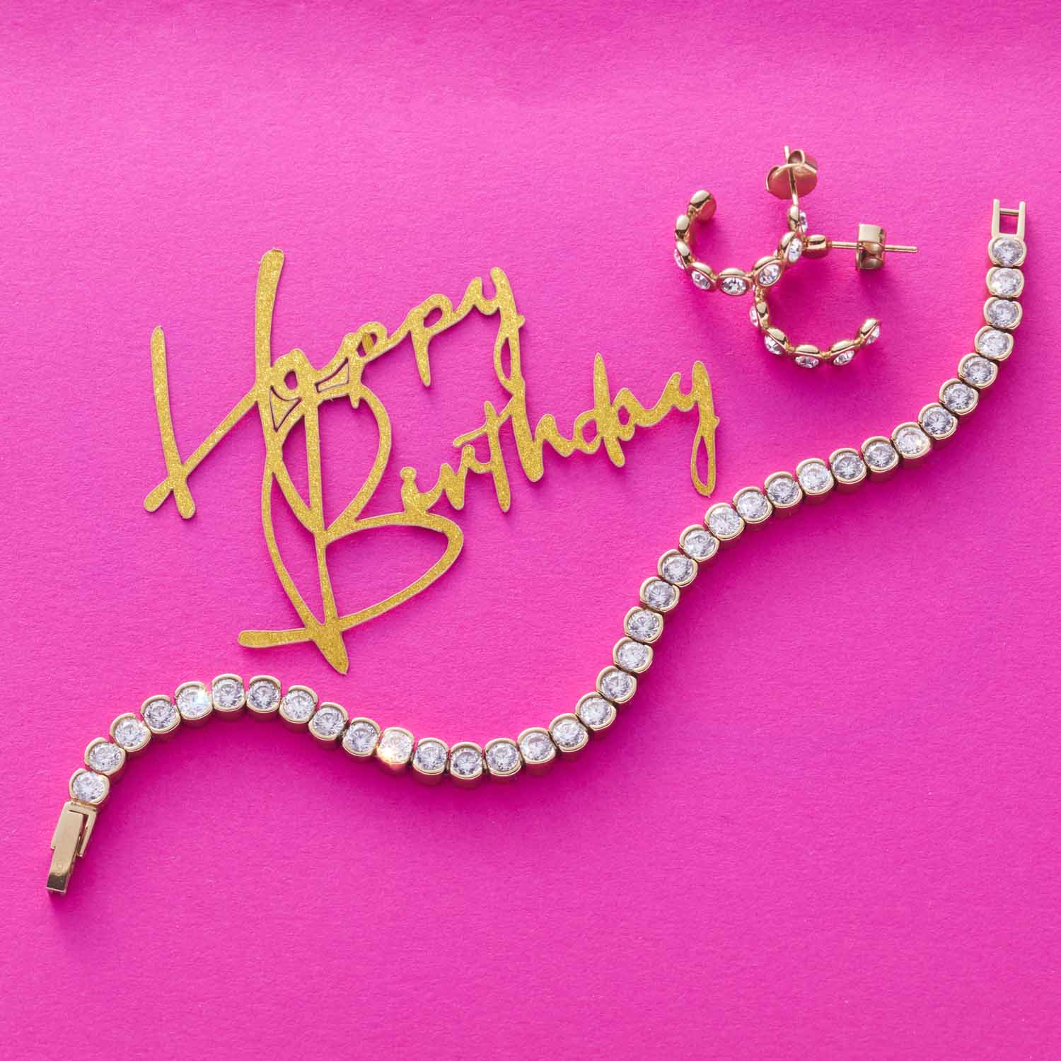 Ohrstecker CREMONA gold und Armband auf rosa Hintergrund mit goldenem Happy Birthday Schriftzug