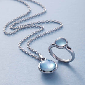 Ring BEA 17 grau blau und Halskette mit Anhänger auf grauem Untergrund