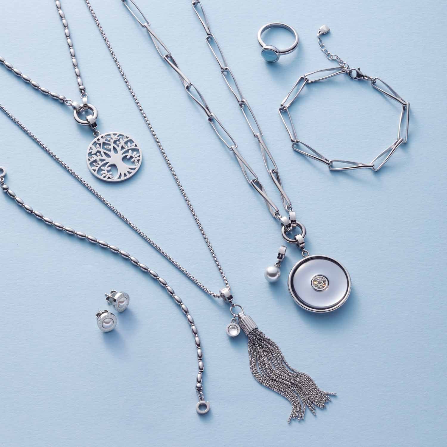 Silberschmuck-Kollektion mit Halsketten, Ringen, Ohrringen und Armband auf hellblauem Hintergrund