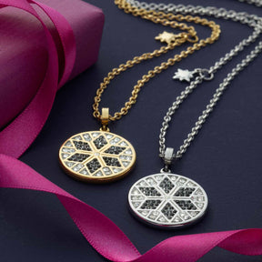 Zwei Halsketten BIELLA mit runden Anhängern in Gold und Silber auf dunklem Hintergrund mit Magenta-Band