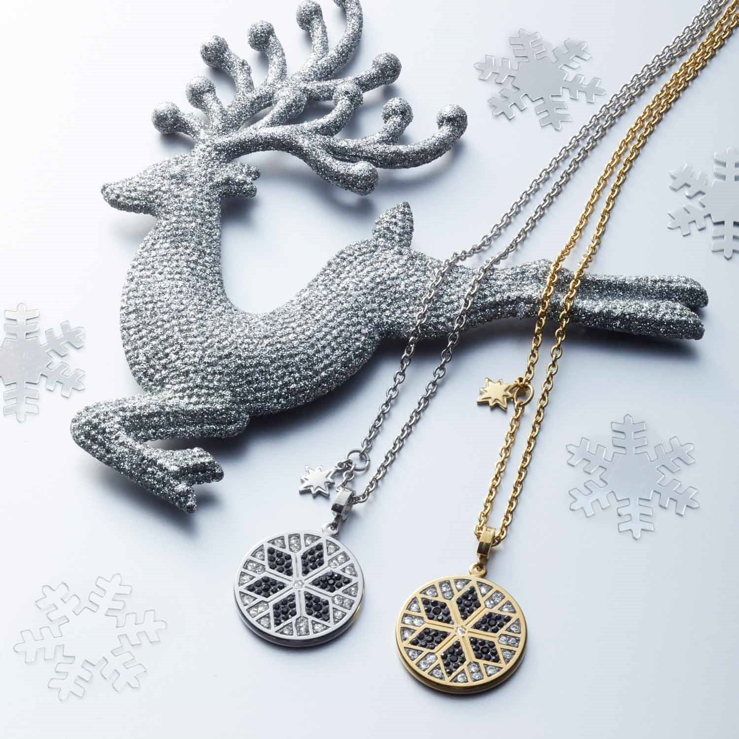Halskette BIELLA mit Schneeflocken-Anhängern in Silber und Gold neben dekorativem Hirsch und Schneeflocken