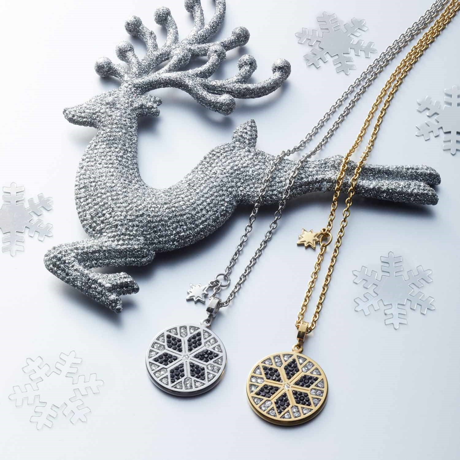 Halskette BIELLA mit Schneeflocken-Anhängern in Silber und Gold, neben dekorativem Hirsch und Schneeflocken-Elementen