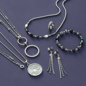 Silberschmuck-Set mit Halsketten, Ring, Armband und Ohrringen auf grauem Untergrund