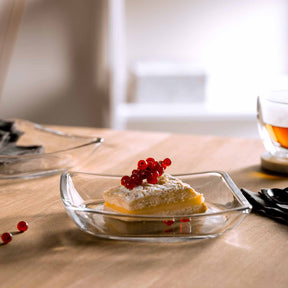 Glasteller mit Dessert und roten Johannisbeeren auf gedecktem Tisch