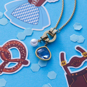 Anhänger JUVINGA gold Clip & Mix mit blauem Glasstein auf blauem Hintergrund mit Dekoelementen