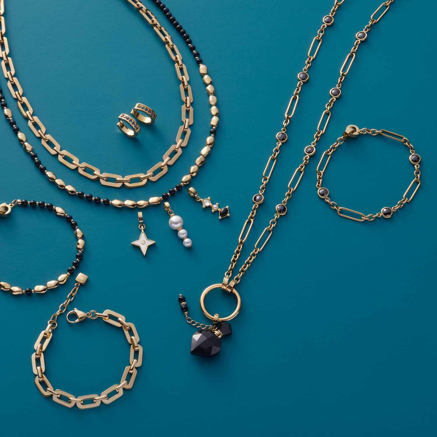 Goldene Armbänder und Halsketten mit Perlen und Glassteinen auf türkisblauem Hintergrund