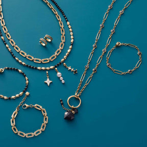 Goldene Armbänder und Halsketten mit Perlen und Glassteinen auf türkisblauem Hintergrund