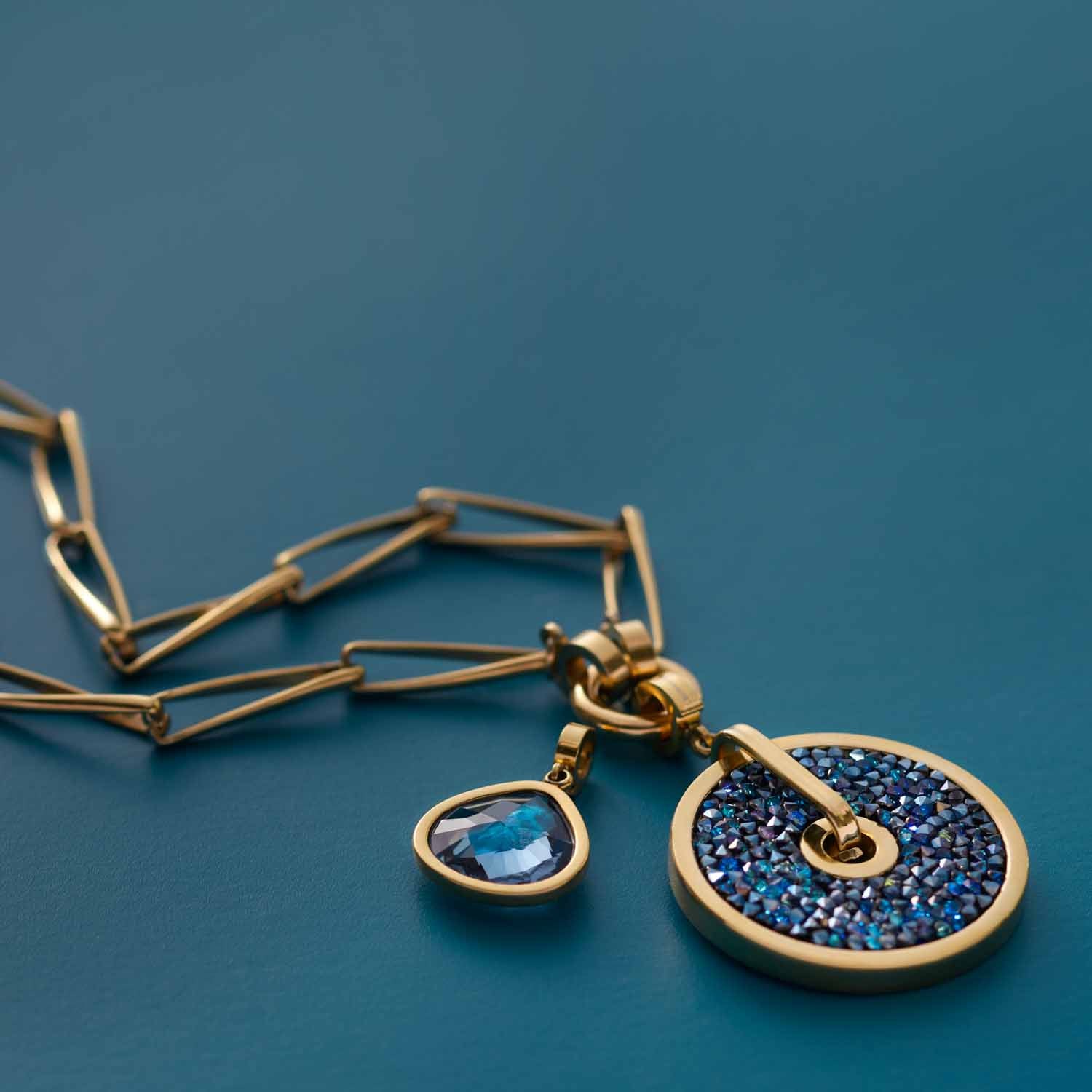 Halskette CONSENZA 70 cm gold Clip & Mix mit zwei blauen Anhängern auf blauem Untergrund