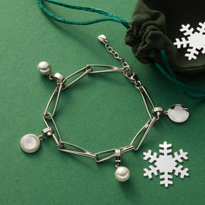 Armband CONSENZA silber mit Perlen und Charms auf grünem Untergrund mit Schneeflocken und Stoffbeutel