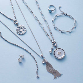 Silberner Schmuck aus der Serie CONSENZA auf hellblauem Hintergrund: Armbänder, Halsketten, Ring und Ohrstecker