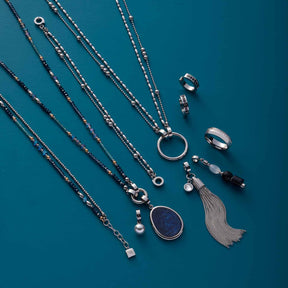 Silberschmuck-Kollektion auf türkisblauem Hintergrund: Ketten, Ringe und Anhänger