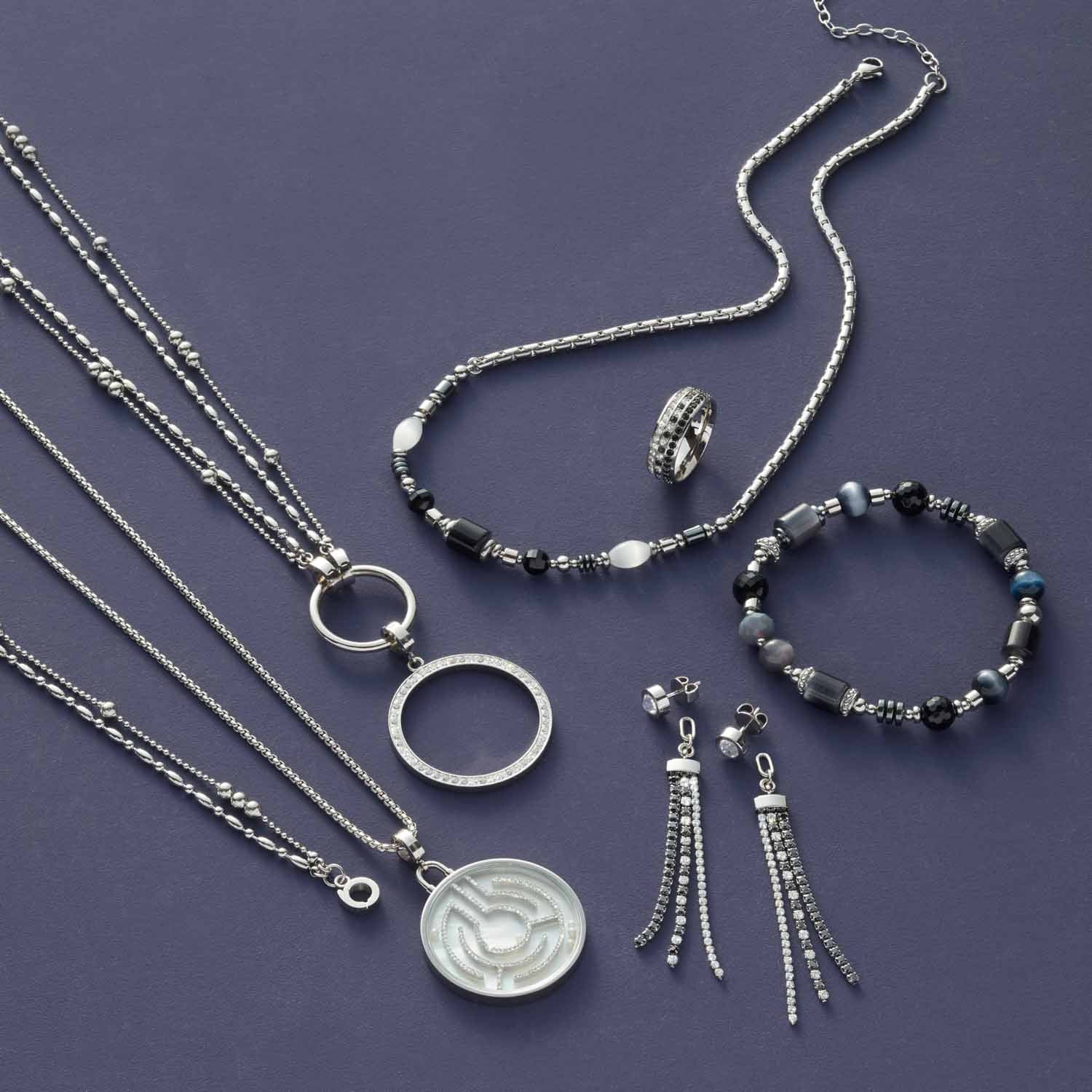 Silberschmuck-Kollektion mit Armbändern, Ketten, Ring und Ohrhänger auf violettem Untergrund