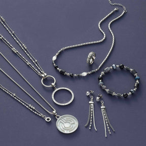 Silberschmuck-Kollektion mit Armbändern, Ketten, Ring und Ohrhänger auf violettem Untergrund