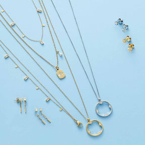 Halskette AMARILA gold mit Glas-Anhängern und passenden Ohrsteckern auf blauem Hintergrund