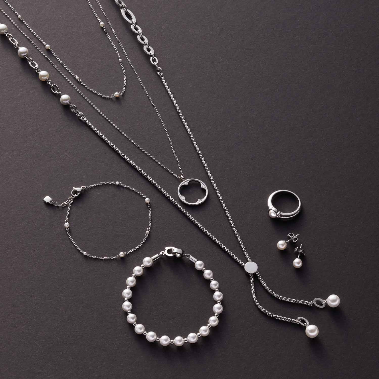 Silberschmuck mit Perlen: Halsketten, Armbänder und Ring auf grauem Untergrund