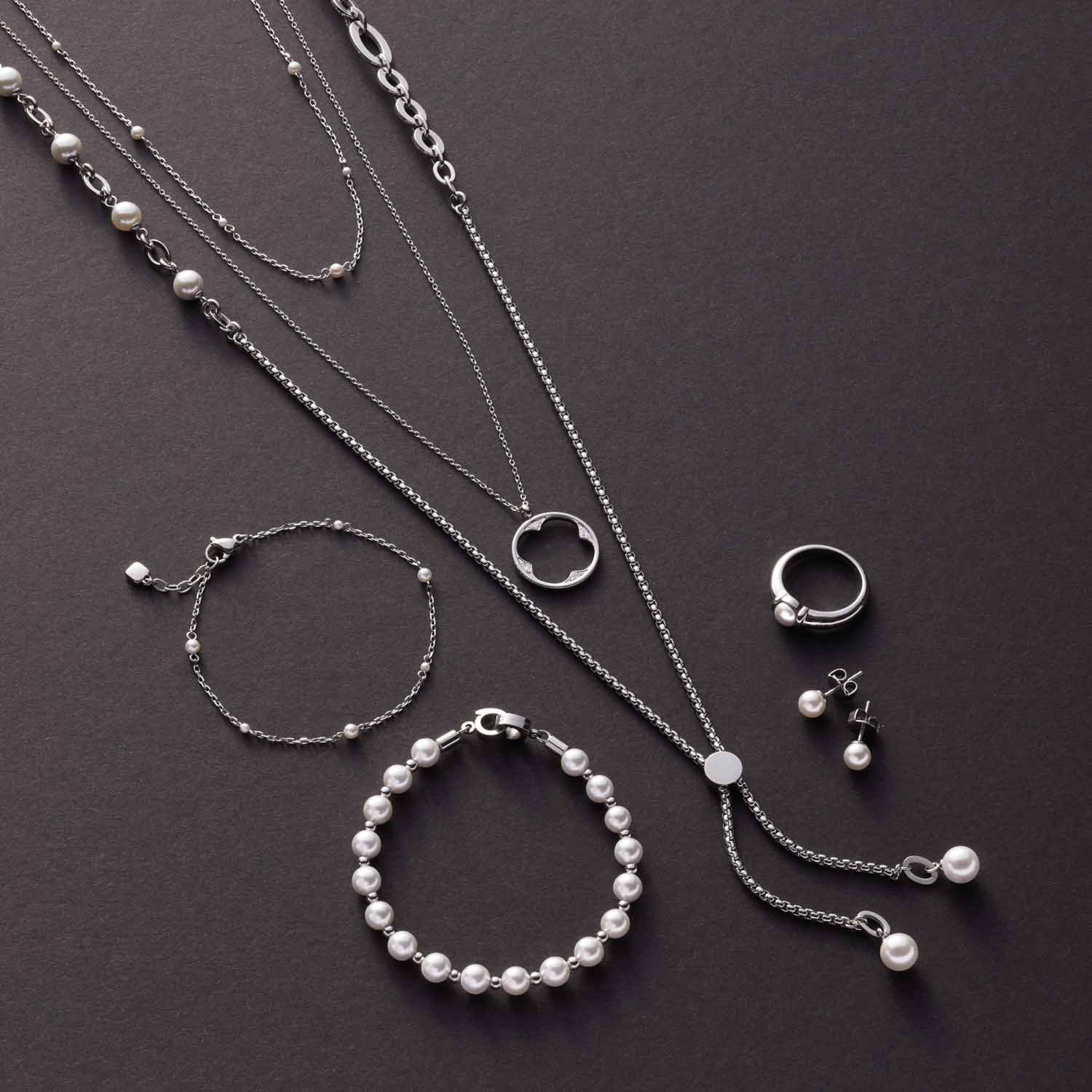 Schmuckkollektion mit Armbändern, Ketten und Ringen aus Glas und Silber auf grauem Untergrund