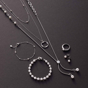 Schmuckkollektion mit Armbändern, Ketten und Ringen aus Glas und Silber auf grauem Untergrund