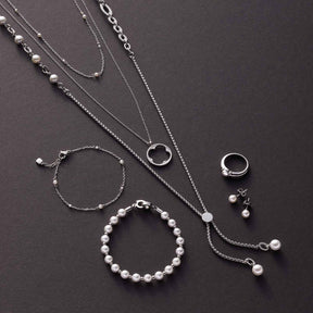 Silberne Schmuckkollektion CAMPAGNOLA mit Halsketten, Armbändern und Ohrringen auf grauem Untergrund