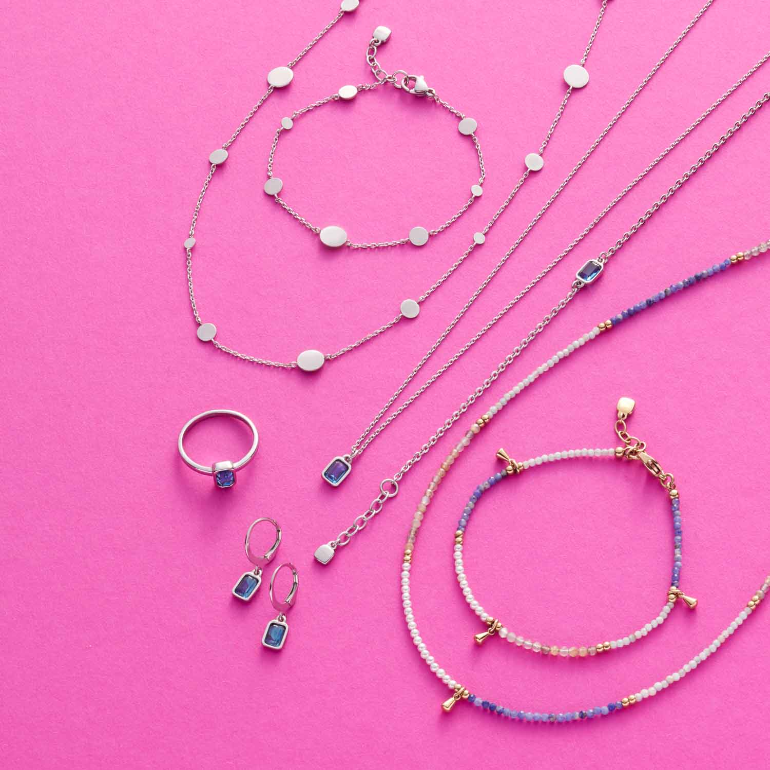 Schmuckkollektion mit Halsketten, Armbändern und Ring aus Glas auf rosa Hintergrund