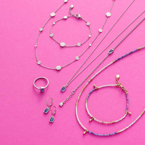Schmuckkollektion mit Halsketten, Armbändern und Ring aus Glas auf rosa Hintergrund