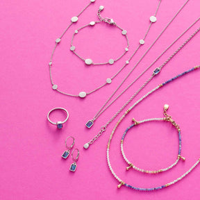 Schmuckkollektion auf rosa Untergrund: Halsketten, Armband und Ring aus Glas in Blau- und Weisstönen