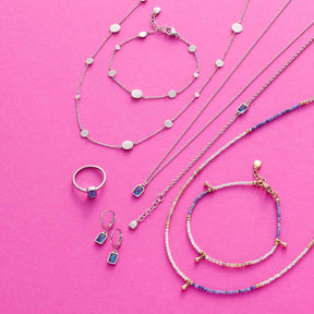 Schmuckkollektion mit Ringen, Ketten und Armbändern aus Glas auf rosa Hintergrund