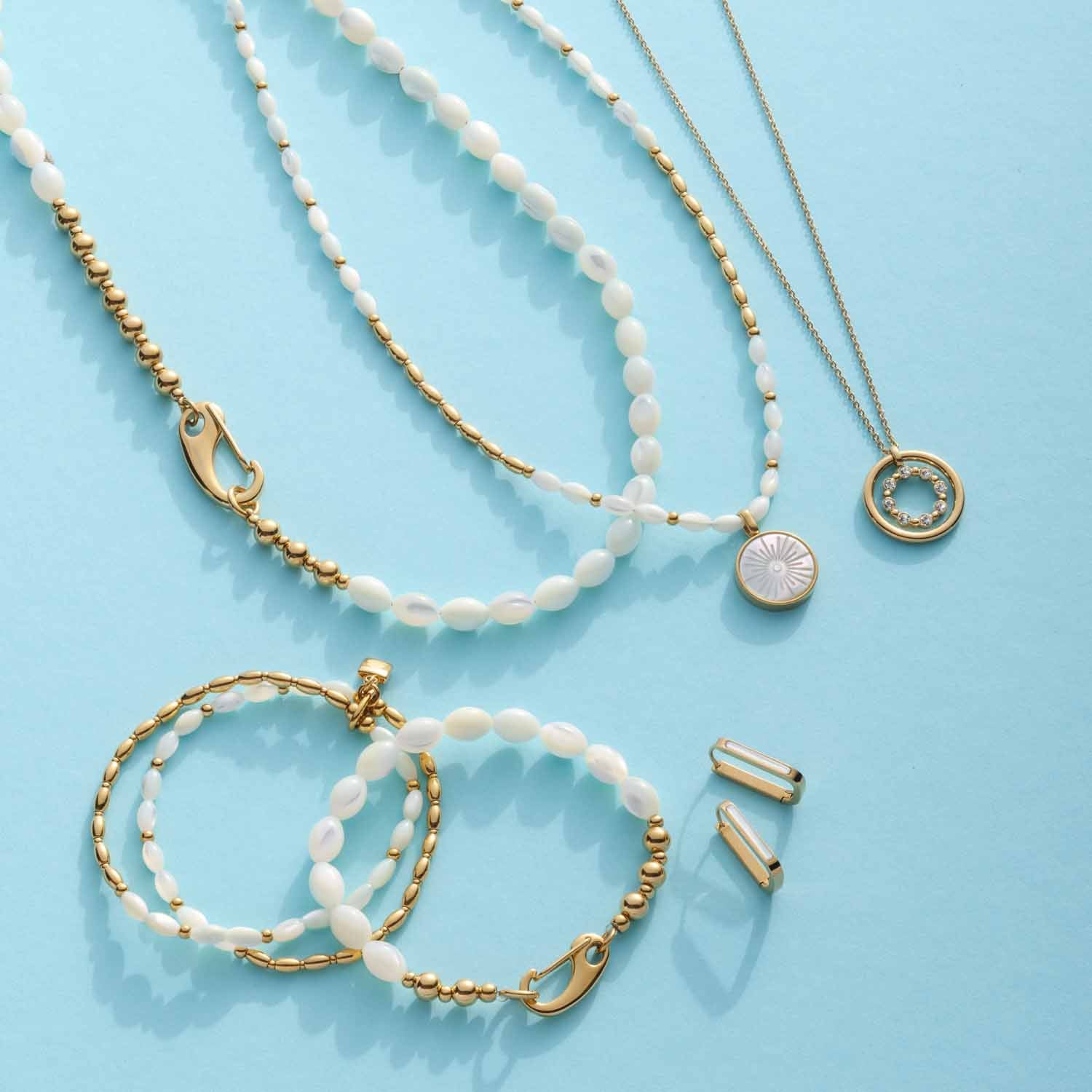 Halskette PATSY mit Muscheln, Armbänder und Ohrringe auf hellblauem Hintergrund