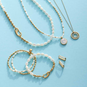 Armband PATSY gold mit Muschelelementen, Halsketten und Accessoires auf blauem Hintergrund