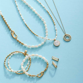 Creolen, Halsketten und Ohrringe mit Muscheln auf blauem Untergrund