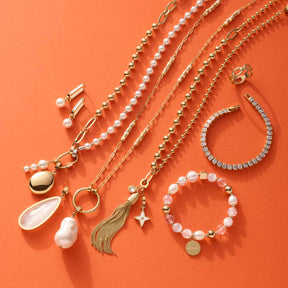 Schmuckkollektion auf orangefarbenem Hintergrund: Ketten, Creolen, Armbänder und Ohrringe mit Perlen und Muscheln