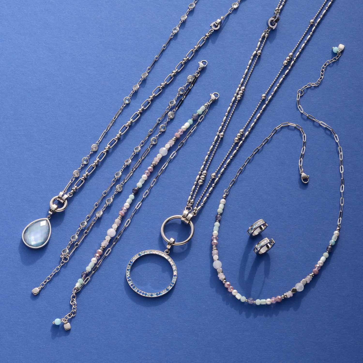 Silberne Ketten und Armbänder mit Glasperlen auf blauem Hintergrund