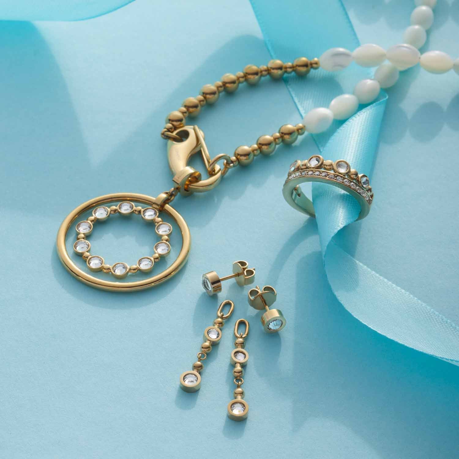 Ring BOBBY 18 gold mit Schmuckset auf blauem Hintergrund